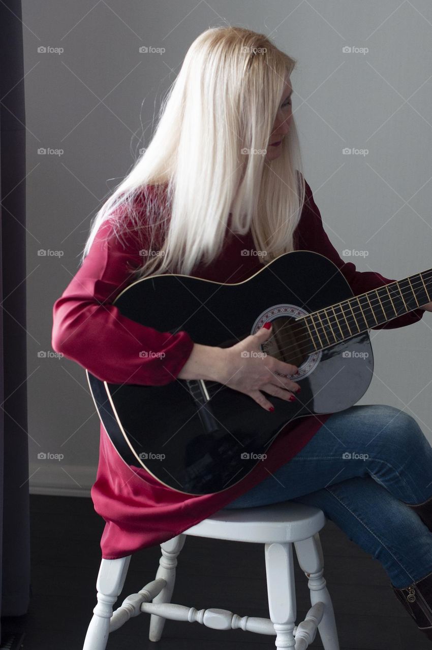 blonde girl in a red dress plays the black guitar