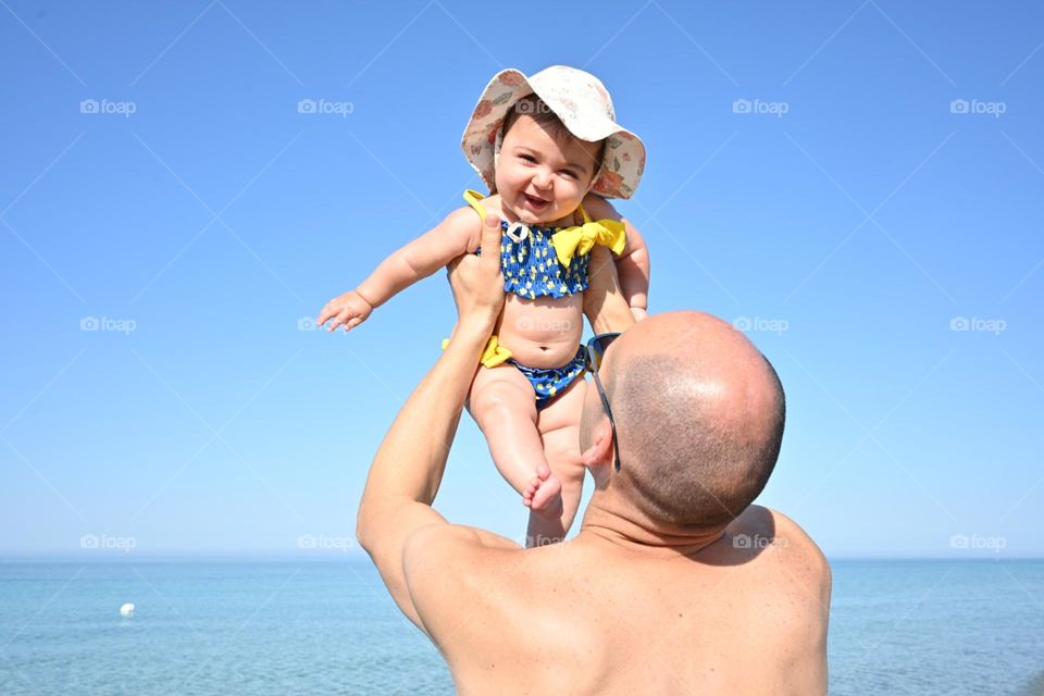 little girl in her father's arms by the sea