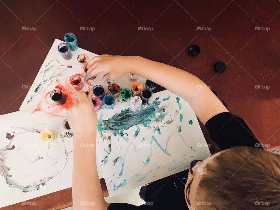 Young boy painting pictures with  colorful finger paints