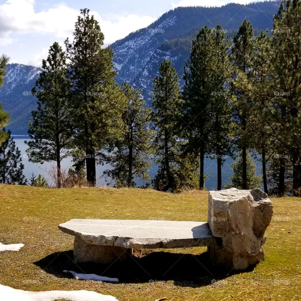 stone bench in park with view of lake and mountain ridge