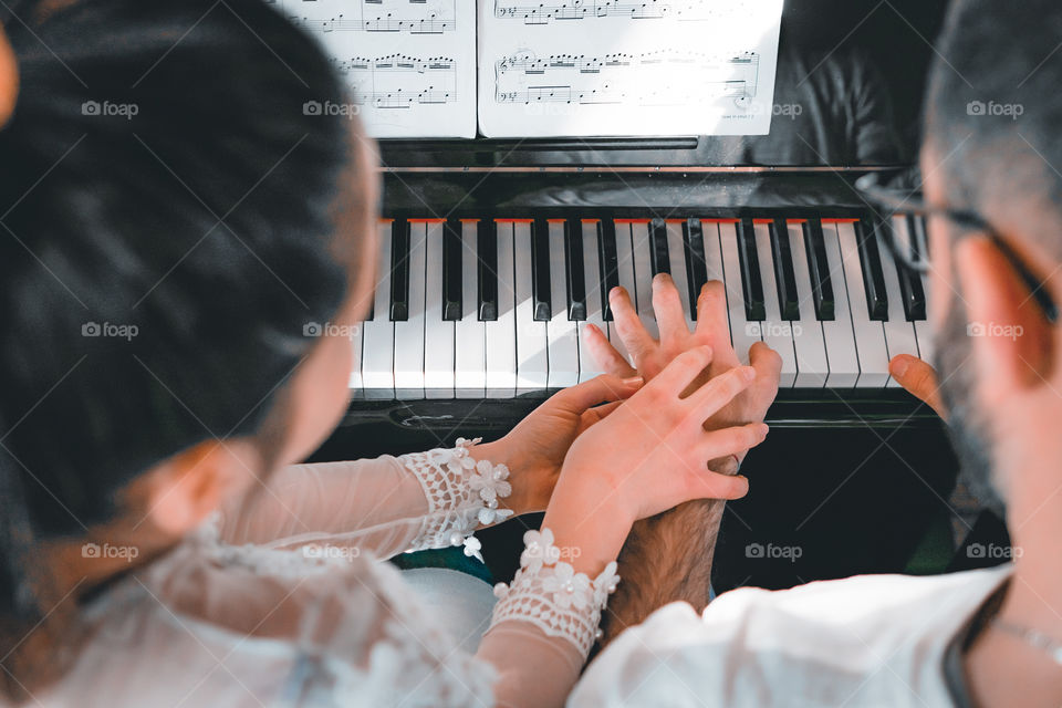 Girl teaches a pupil to play the piano