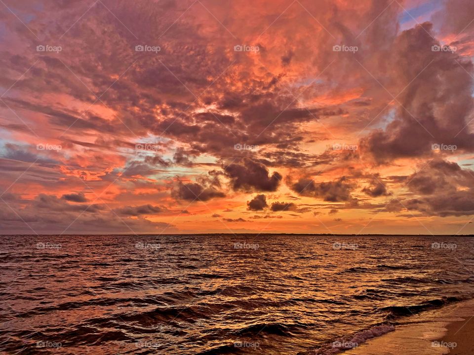 Near dusk, intense coral pinks, reds, and peachy oranges have draped the horizon. Amid the colors are clouds that look like falling sheets of fabric, floating as if they are trying to assemble a parachute for our sinking star.