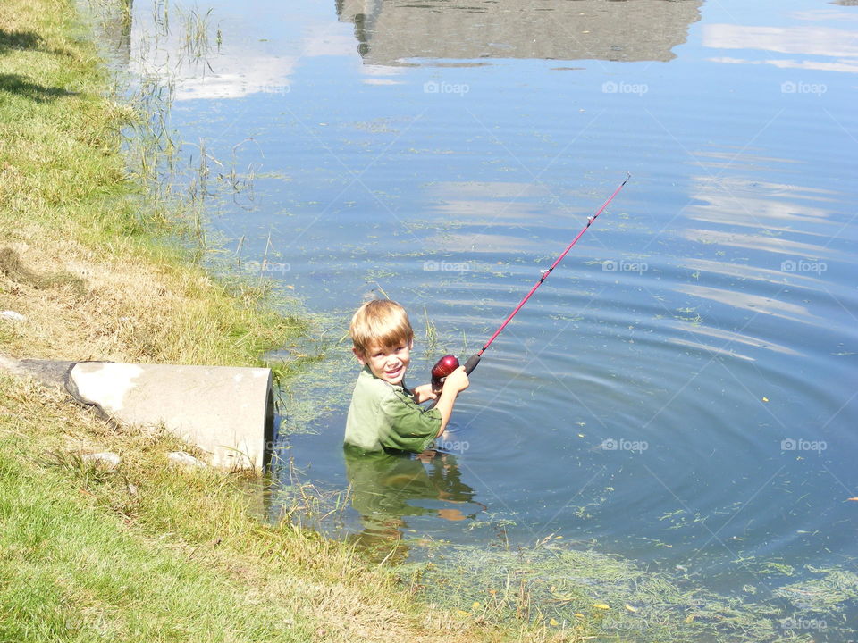 This boy was standing on the concrete drain, lost his balance and fell in the pond.