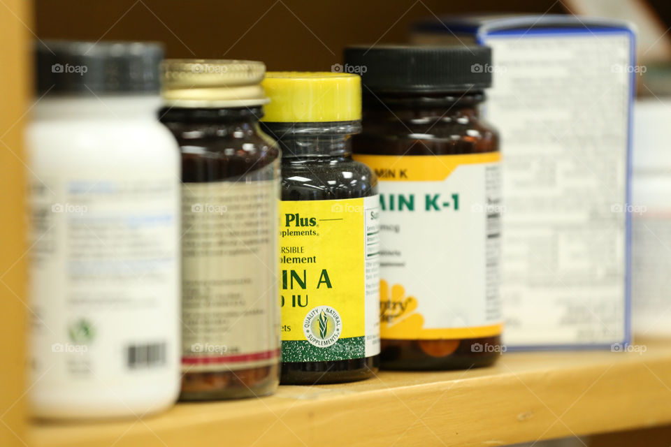 Medicine pill bottles on a shelf with vitamin bottles