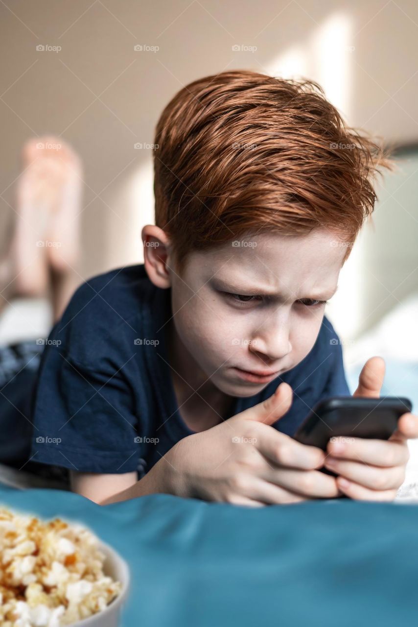 boy with beautiful red hair watering seedlings