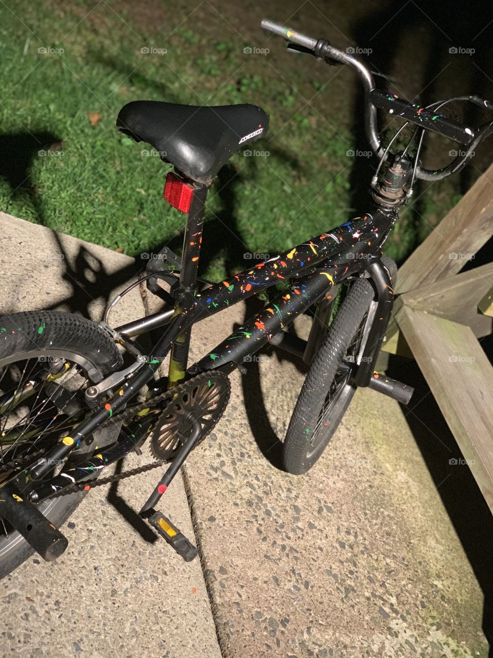 A bike that was spray painted black and with other multiple colors 