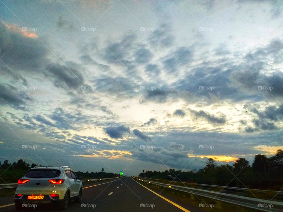 car on a highway with sunsetting sky