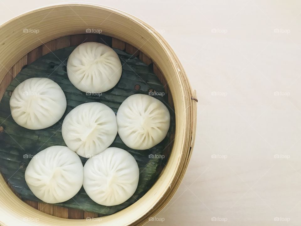 Xiaolongbao or soup dumpling is a one type of chinese steamed bun which filled with hot soup in small bamboo basket container with copy space on right side of frame