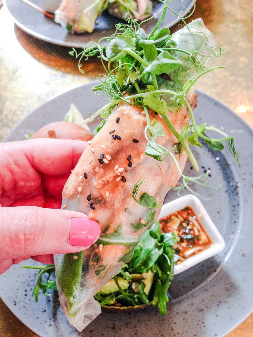 Close-up of woman's hand holding vegan springroll