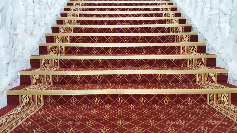 Staircase with symmetrical pattern in red and gold, marble handrails 