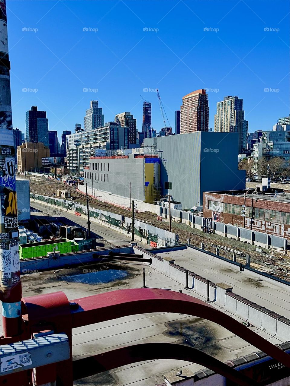 These are the “Long Island Railroad” tracks seen from the “Pulaski Bridge” in LIC, Queens, NY. The big rectangular building houses “iFly”, an indoor flight simulator and in the distance behind LIC we see “Manhattan”. 2024. Hypnotic Productions