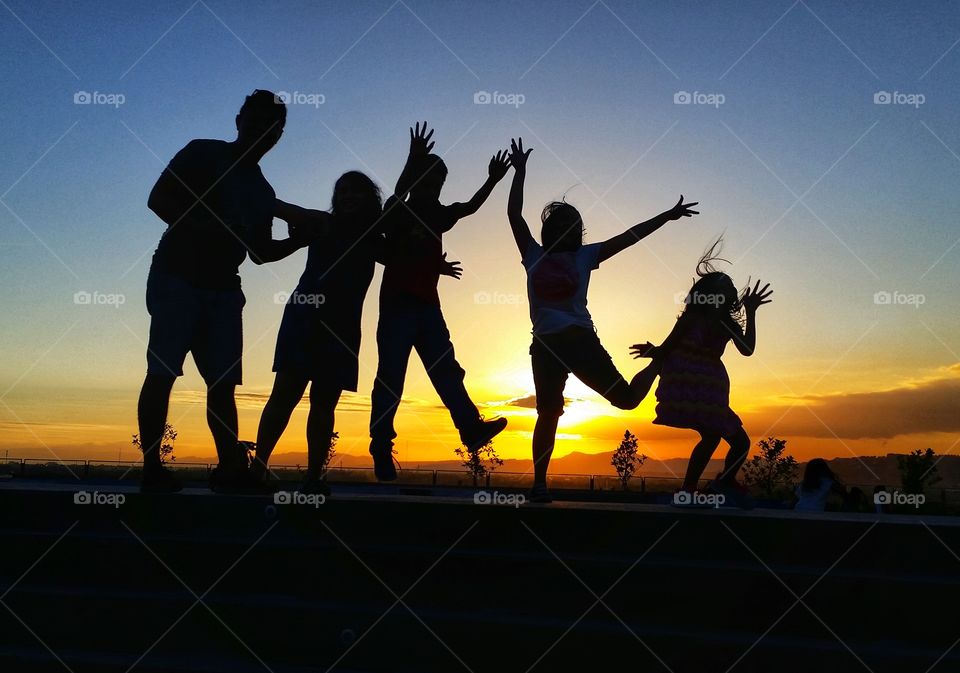 A silhouette of people in action with the sunlight in the background.