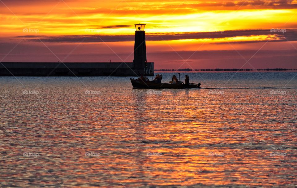 fishing boat near lighthouse during sunrise over the baltic sea in Gdynia, Poland