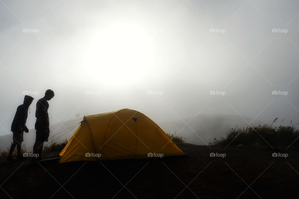 Silhouette of Tourists and yellow camping tent in the mist