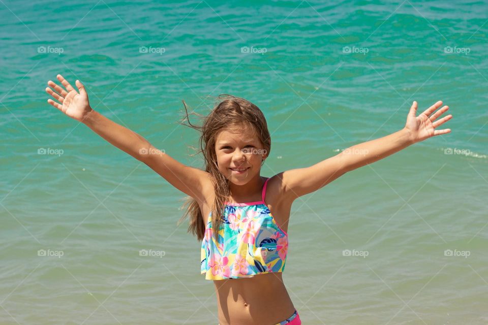 Beautiful happy child with open wide hands on sea background