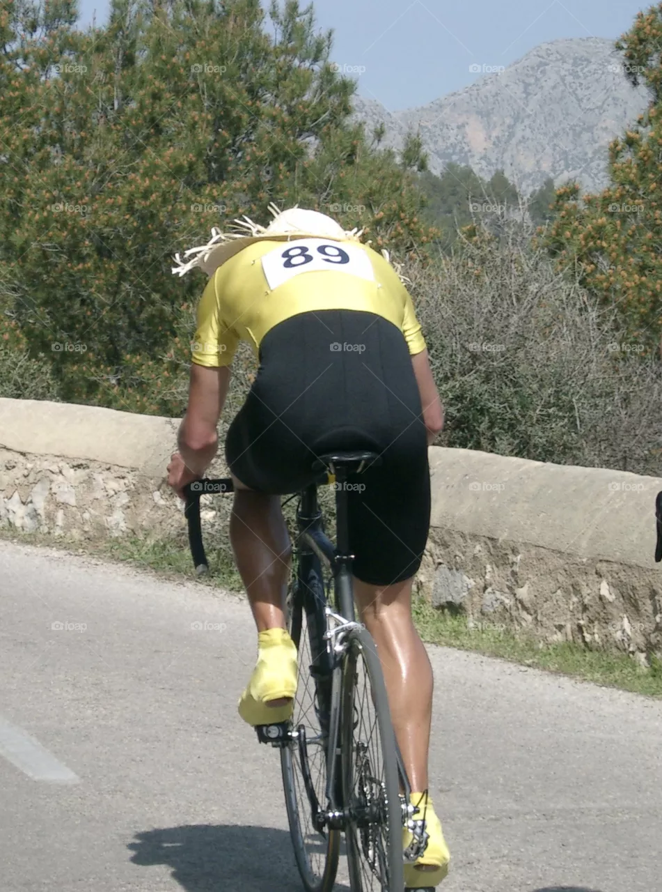 A Cyclist with a funny hat riding uphill at Majorca 