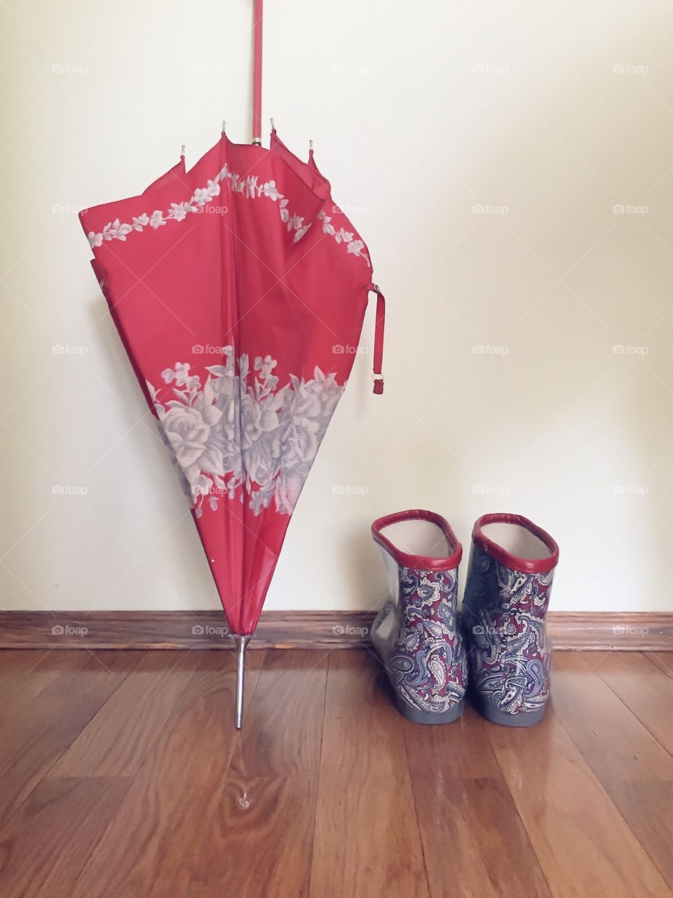 Wet rubber boots and umbrella near the wall on a rainy day 