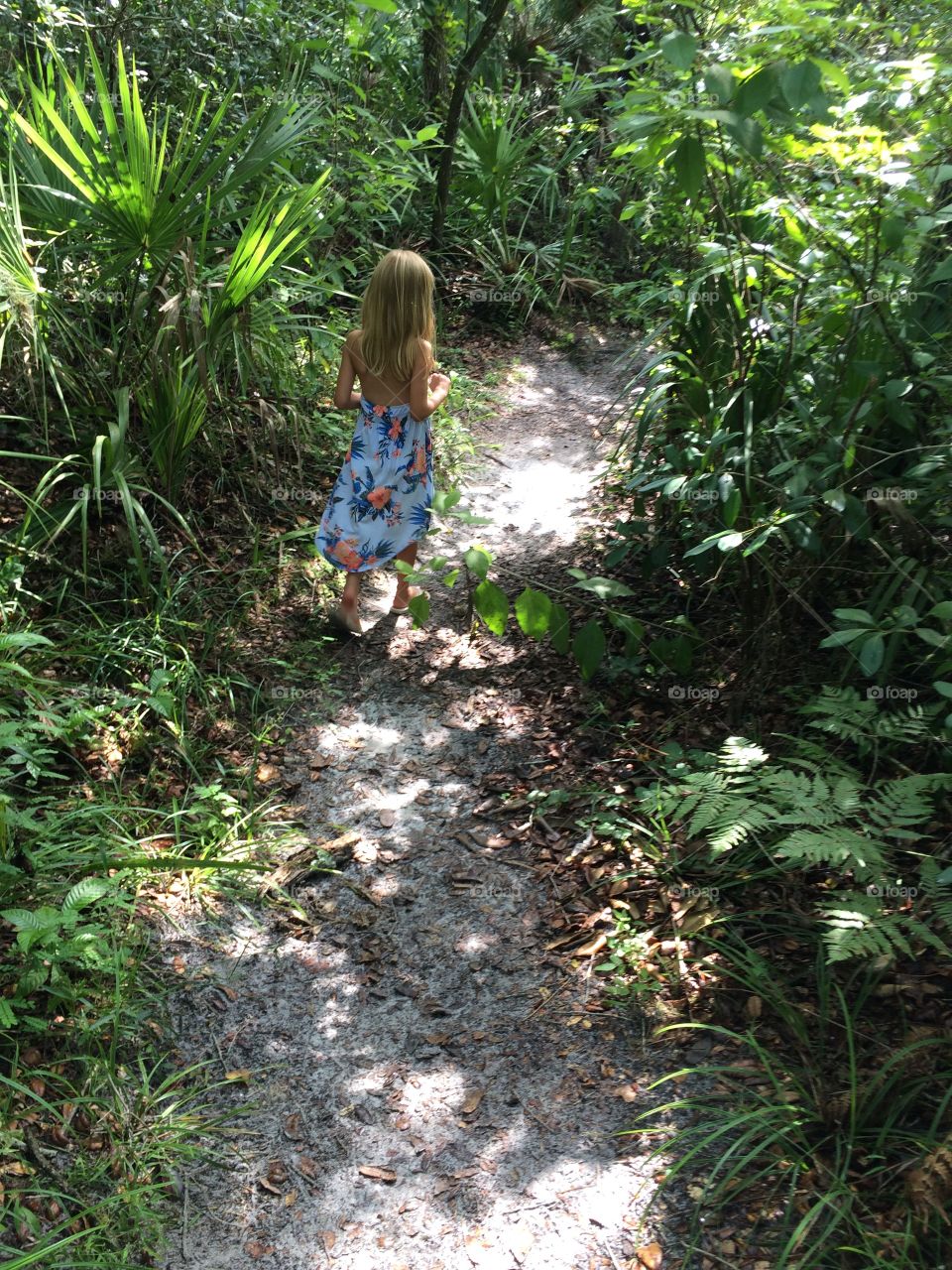 Little girl walking down path in the woods 