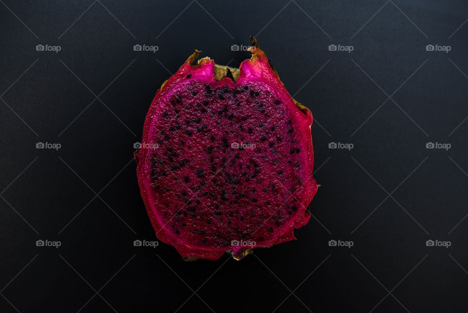 Flat lay of a half of a dragon fruit on a black counter