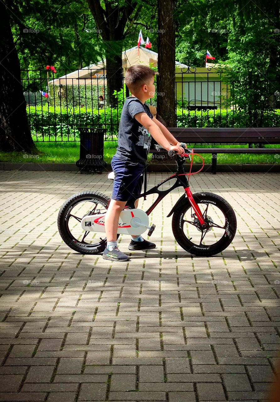 Bicycle and cyclist.  A little boy on a bicycle stopped and looks to the side