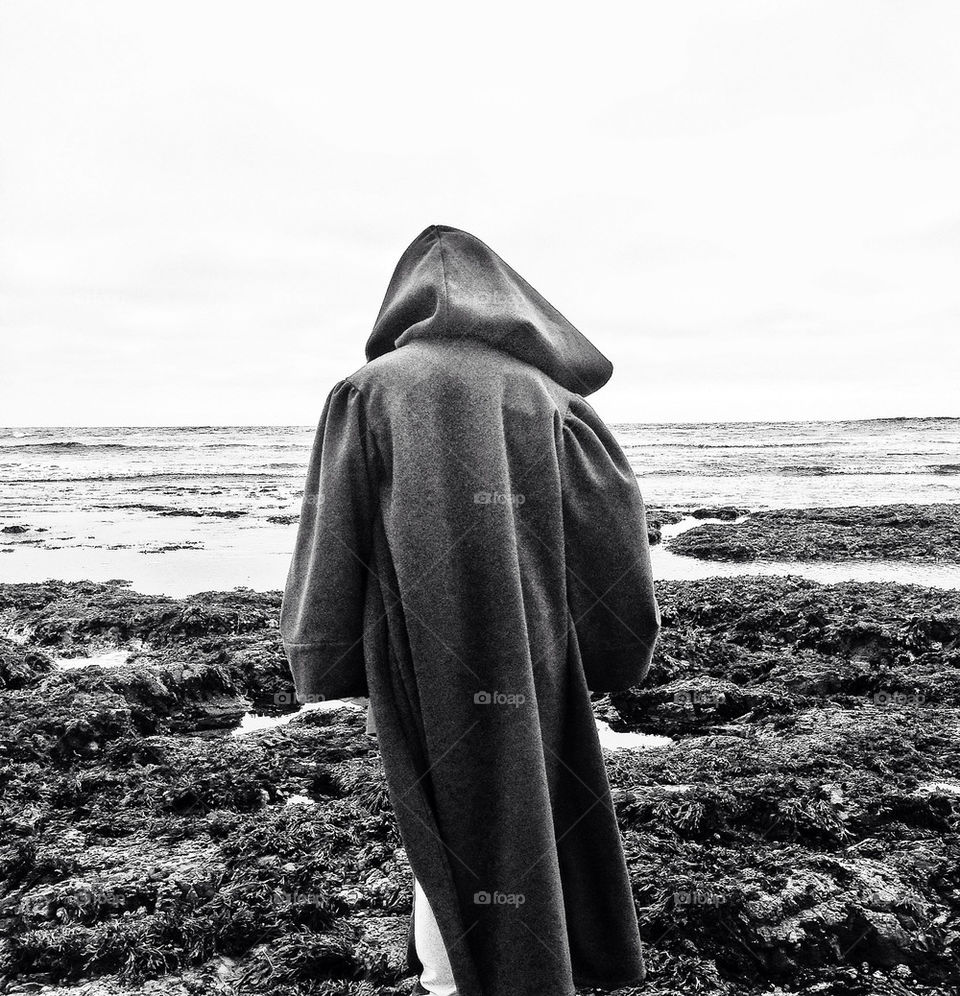 Mysterious hooded figure looking out to sea
