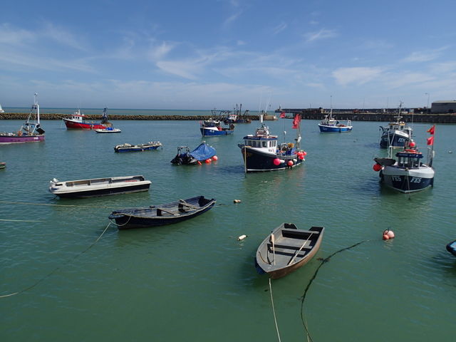 Fishing boats tied up or anchored in the calm harbor in Folkestone England on a sunny summer day. 