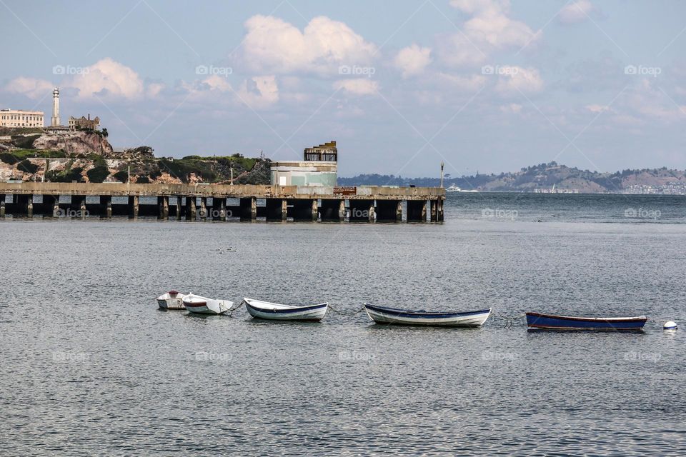 Line of row boats in the San Francisco Bay, almost like a momma duck and her chick swimming through the water.