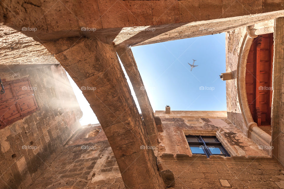 Aeroplane flying above old medieval masonry buildings in downtown district in Rhodes town. Island of Rhodes. Greece.