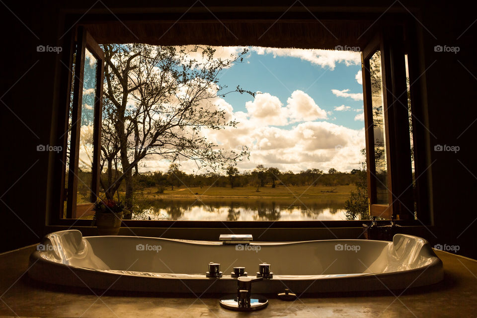 Me time is bath time! Love a bubble bath and nature to relax and slow down from the busy life we live. Image of a bath tub at a large window with dam and bush outside