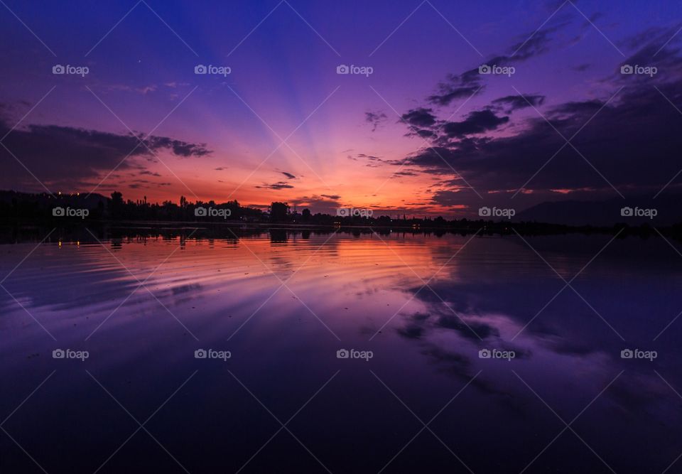 mesmerizing purple and orange hue of sunset in the evening by the lake side and the reflection