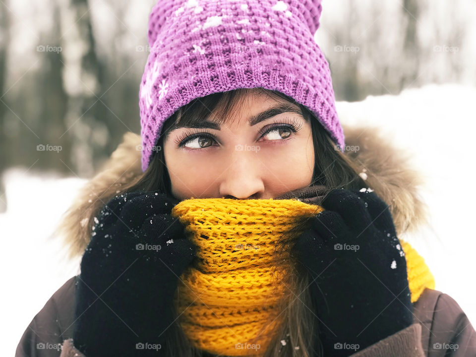 Portrait of a young woman snuggling up in winter clothes 