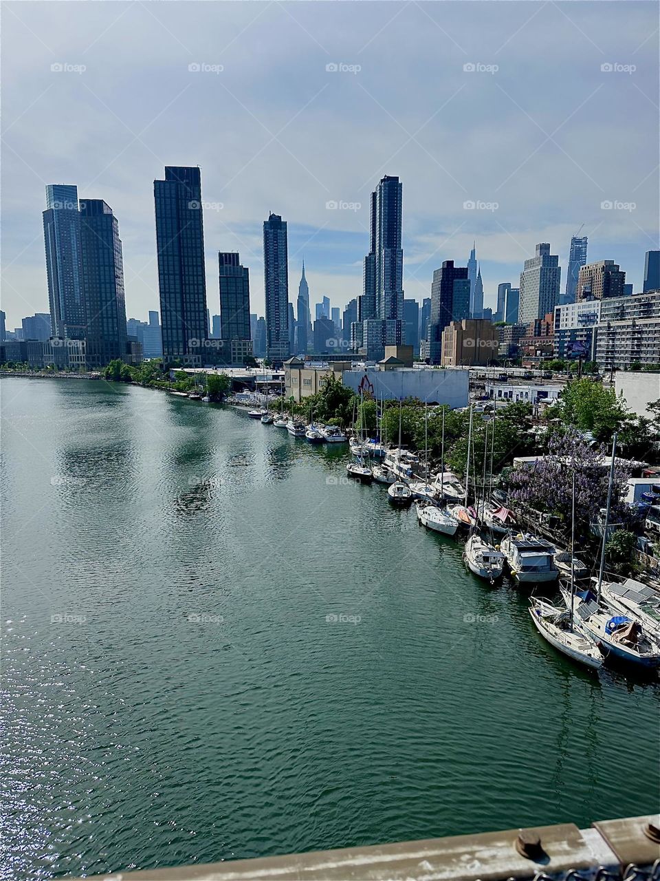 This is “Newtown Creek” seen from the “Pulaski Bridge” that connects LIC, Queens to “Greenpoint”, Brooklyn. Across the “East River” in the far distance we see “Manhattan” including the “Empire State Building”. 2024. Hypnotic Productions