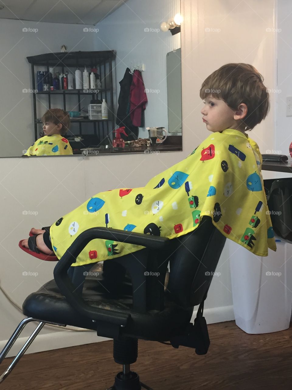 Anxious boy sitting on barber chair
