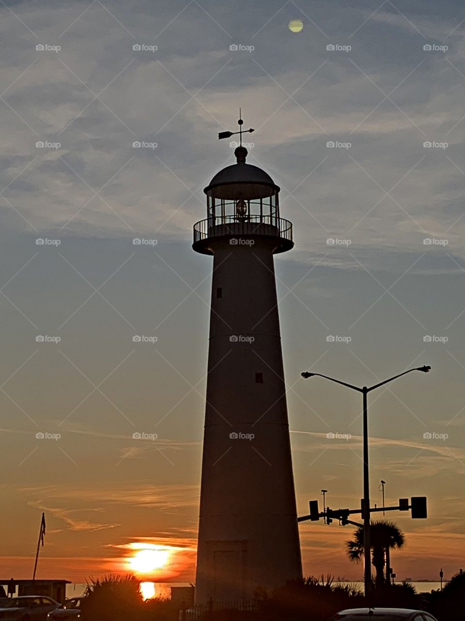 The sunlight and the moonlight - the moon and sun are out together casting around the lighthouse 