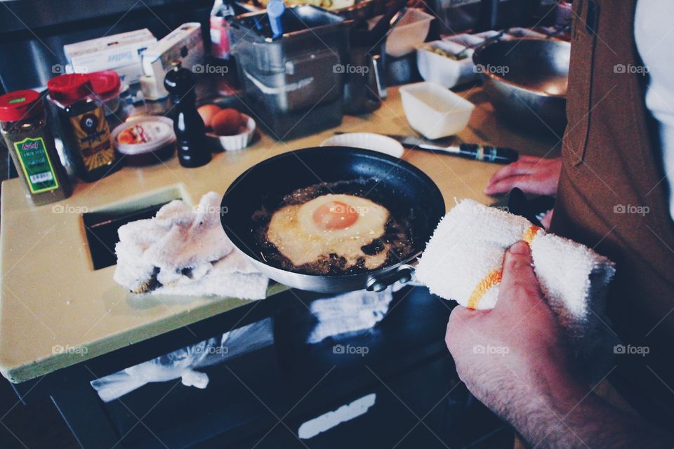 A Cook Cooks his Egg. A cook cooking an egg sunny side up