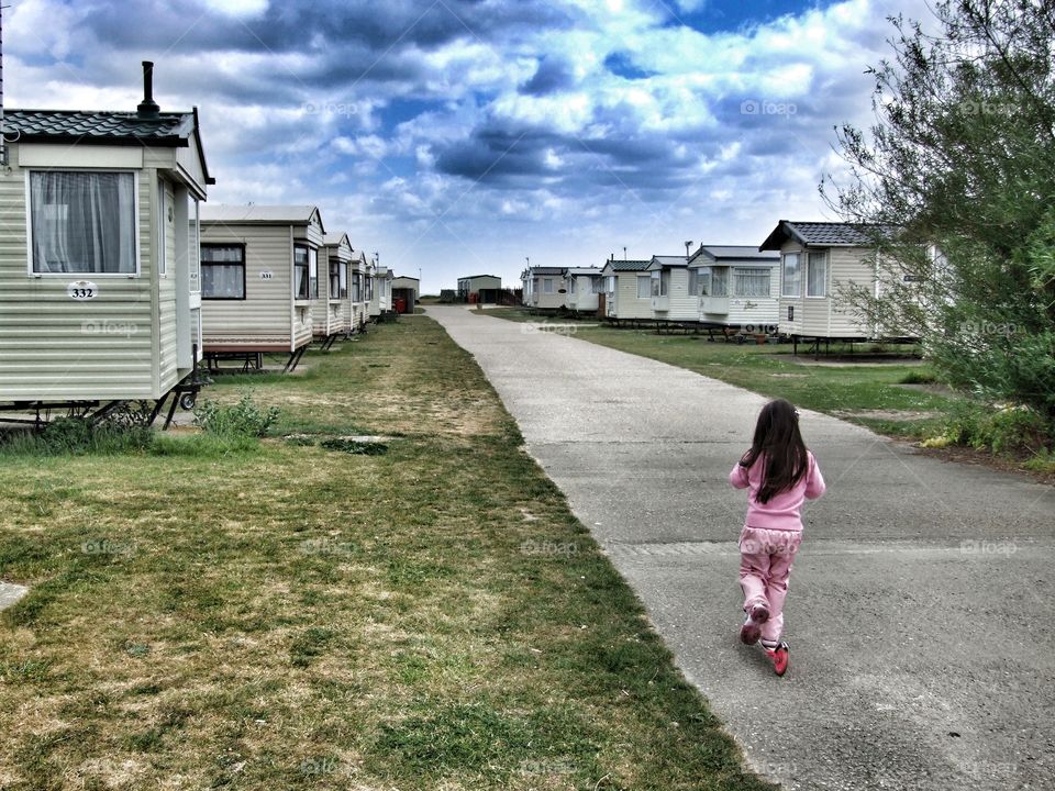 Girl riding he scooter down a path at a holiday resort.