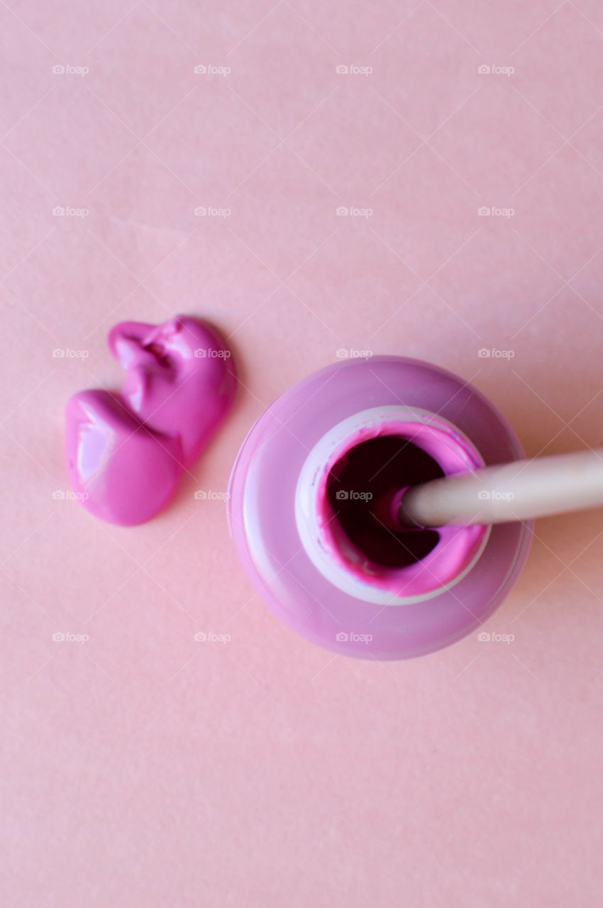 Pink paint bottle with paintbrush on paper