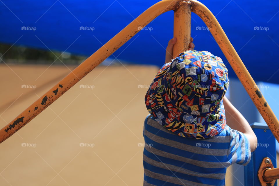 Little boy of five years old playing in playground and wearing sunhat 