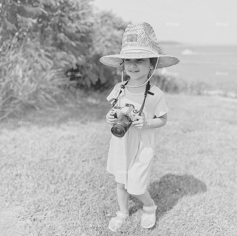 Black and white portrait of a toddler girl with camera, toddler practicing photography, toddler girl wants to be a photographer, toddler with a Canon film camera 