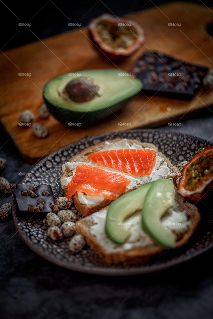 Dietary sandwiches of grain toasts with cream cheese, fish, avocado and passion fruit 