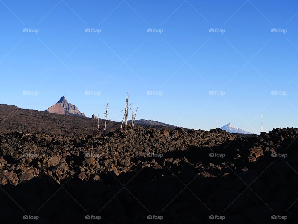 A vast lava rock field leads to the jagged peak of Mt. Washington in Oregon’s Cascade Mountain Range on a sunny fall morning with clear blue skies. 