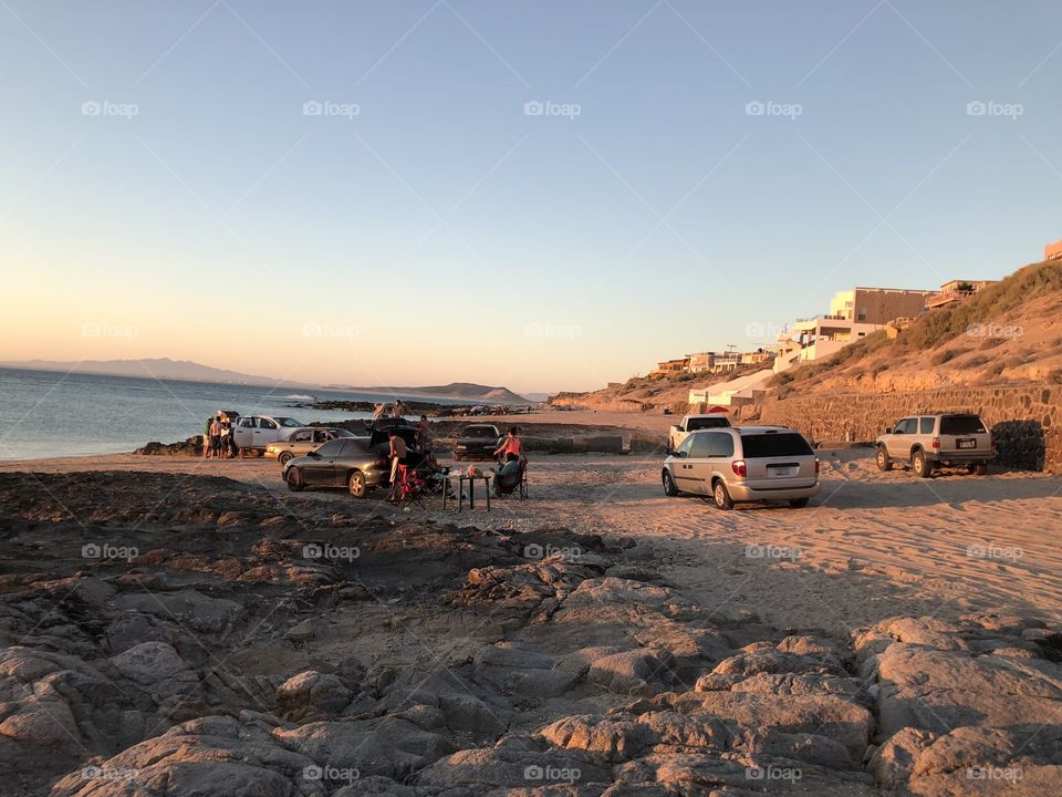 A rocky beach in Mexico with a family preparing a barbecue