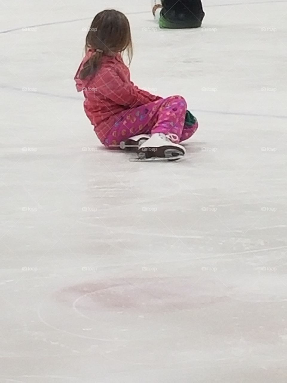 girl sitting on ice rink on skates