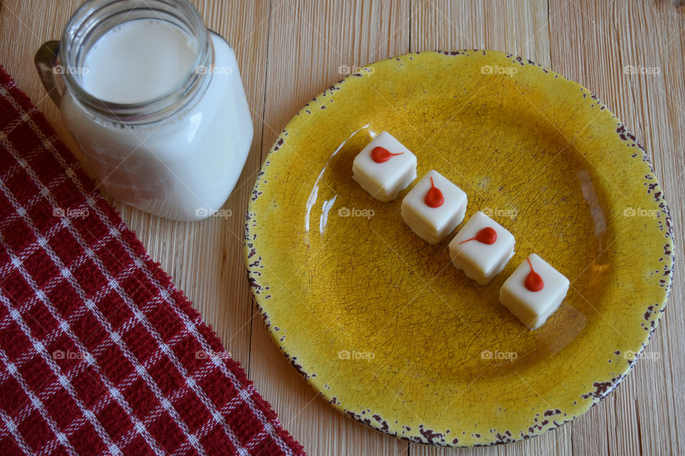 Cold glass of milk with plate of cake bites.
