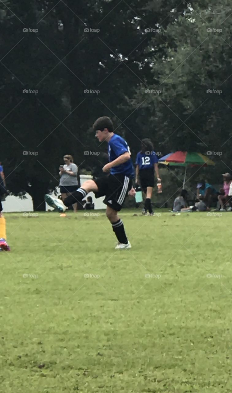 Action shot of a very handsome athletic teen boy kicking during his soccer game. 
