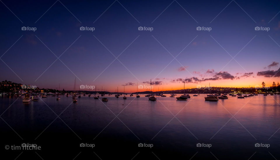 The winter sunrise creeps into Sydney Harbour while the yachts moored in Rose Bay sleep