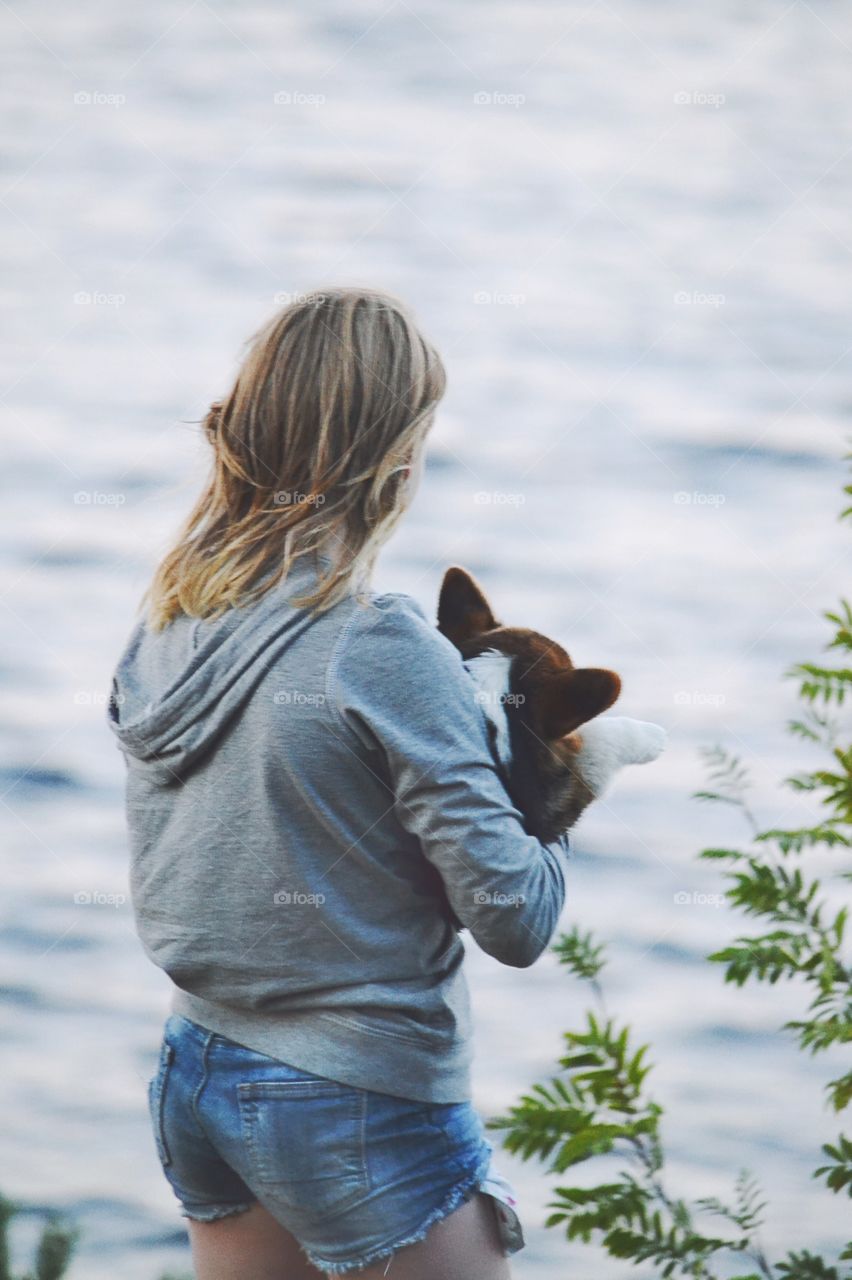 Girl with a puppy. Girl looking over the water