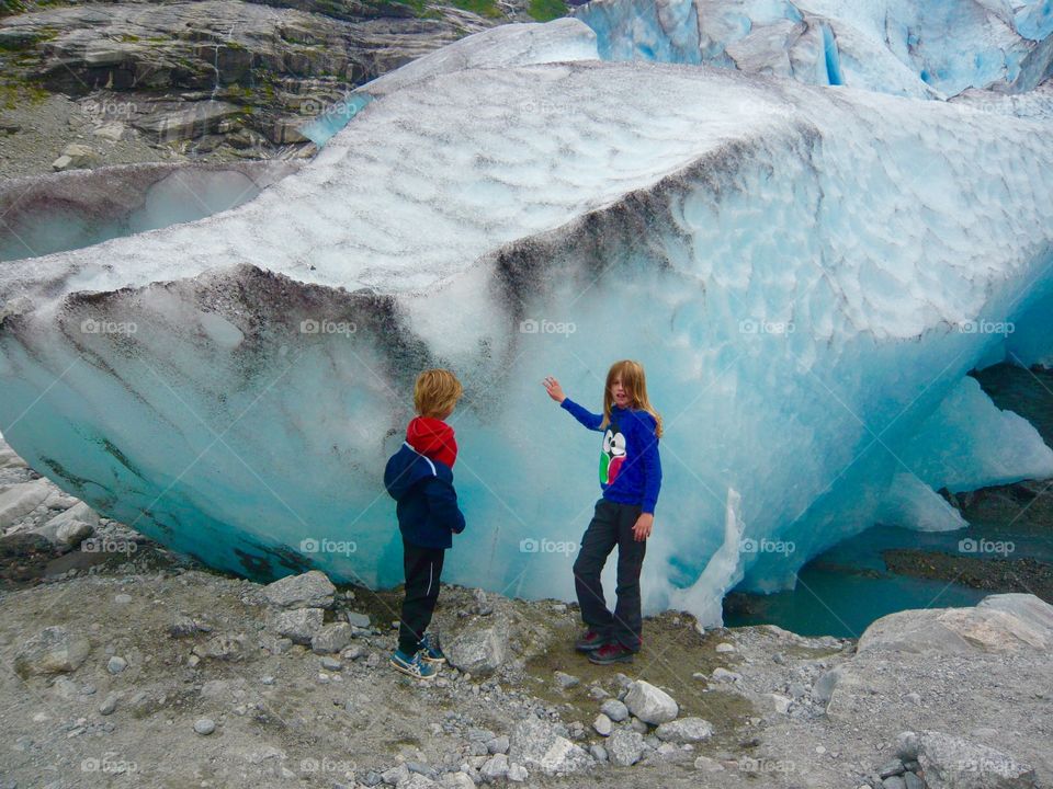 Little boy and girl standing near ice glacier
