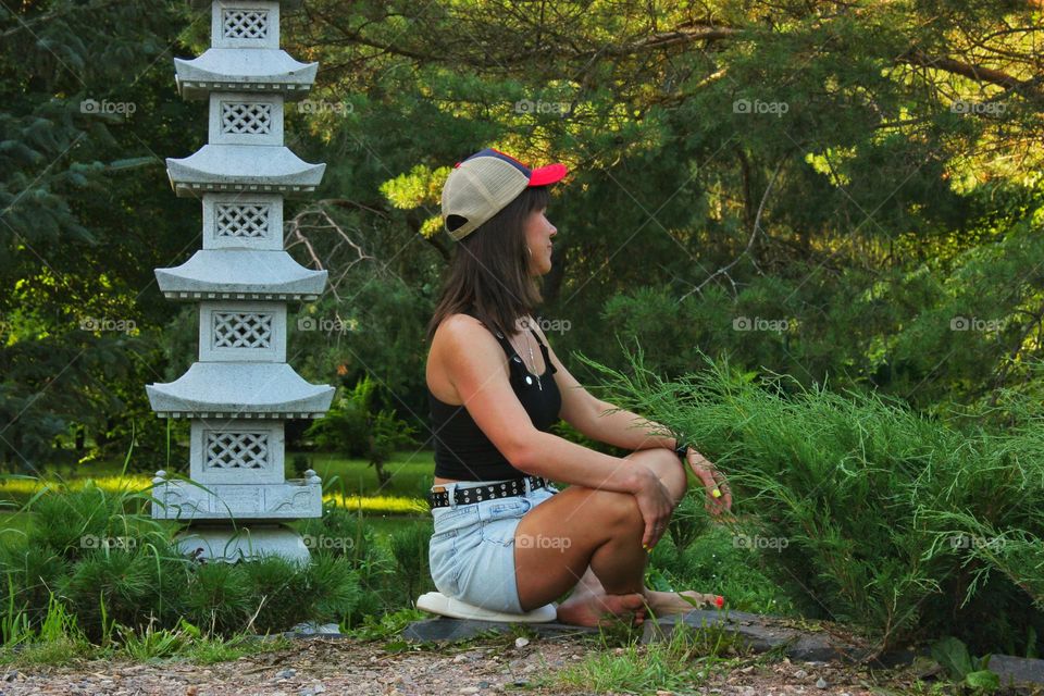 a girl in a Japanese garden sits in a meditative pose and relaxes