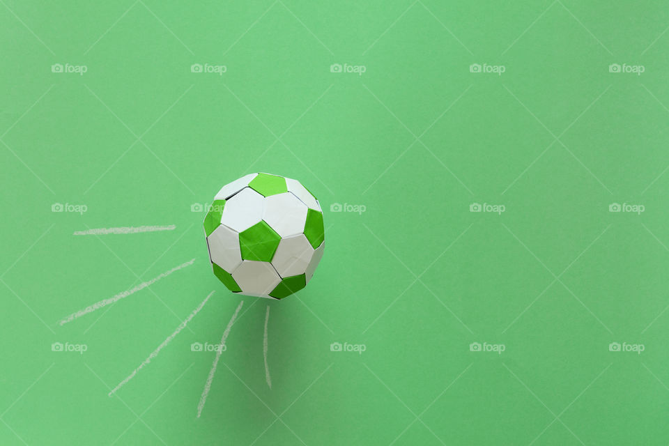 Paper soccer ball flying into goal painted by chalk on green background. Origami. Paper craft. Soccer game concept.